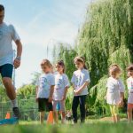 Children in a park learning sports with a coach on a sunny day.